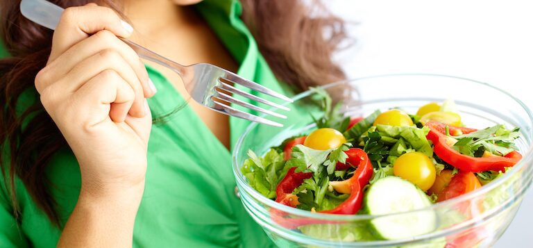 A woman eating a salad whilst being more mindful